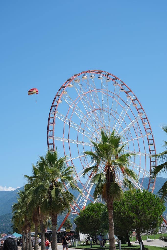 Enjoy a vibrant summer day at Batumi with a view of the Ferris wheel and palm trees.