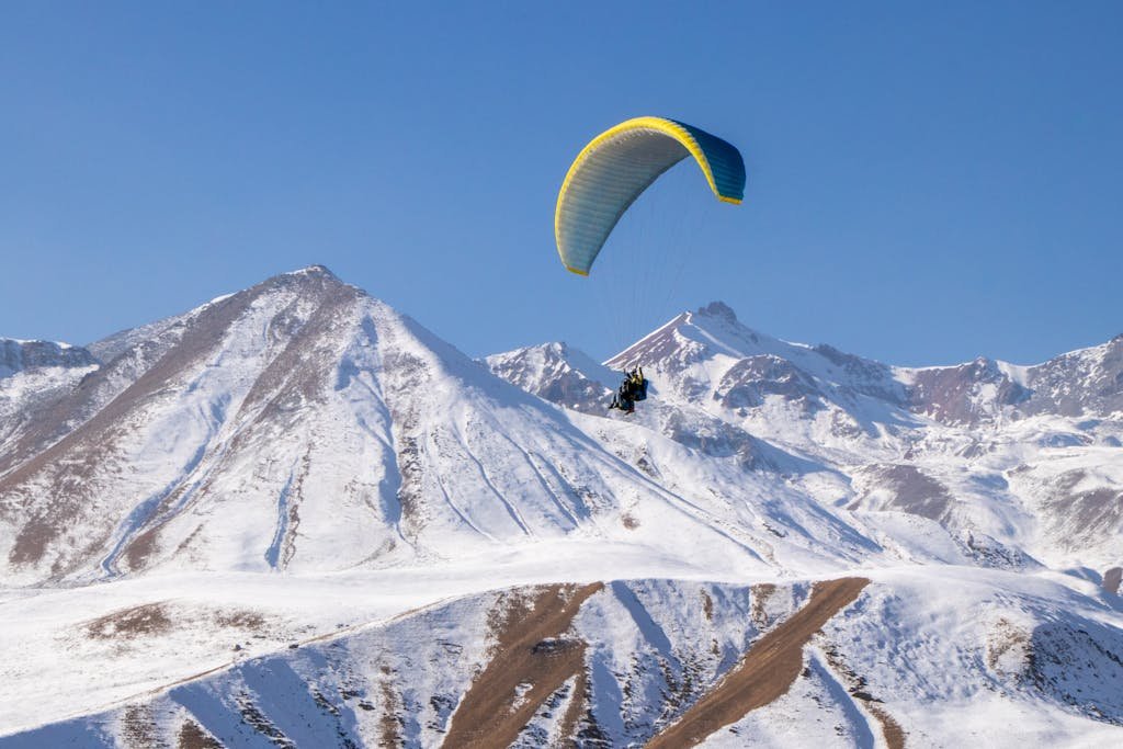 Experience the thrill of paragliding over snow-capped Gudauri mountains in Georgia.