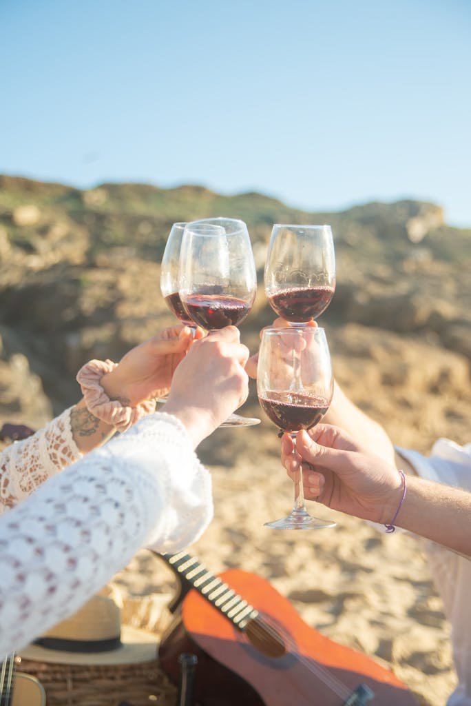 Friends toasting with wine glasses on a sunny beach in Portugal. Celebratory and joyful moment captured outdoors.