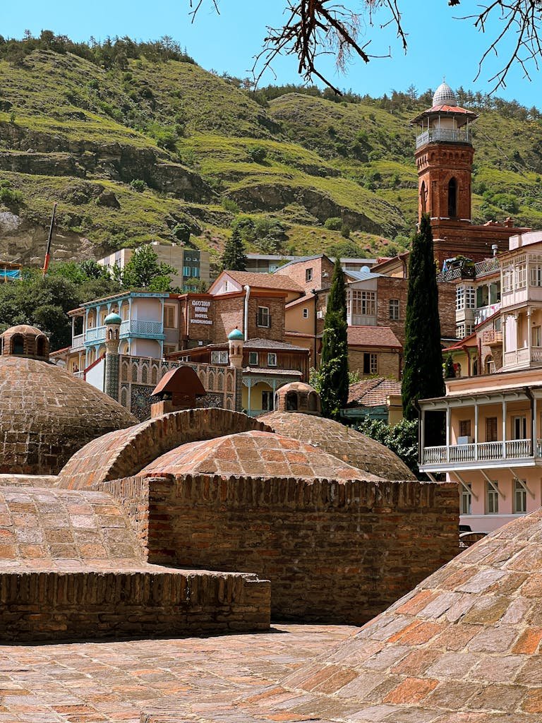 Scenic view of the historic sulfur baths in Tbilisi, Georgia, surrounded by colorful houses and lush hills.