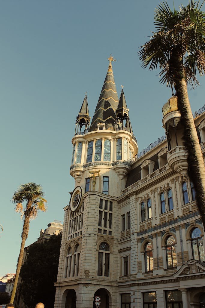 Vintage-style shot of a landmark tower with clock and palm trees under clear sky.