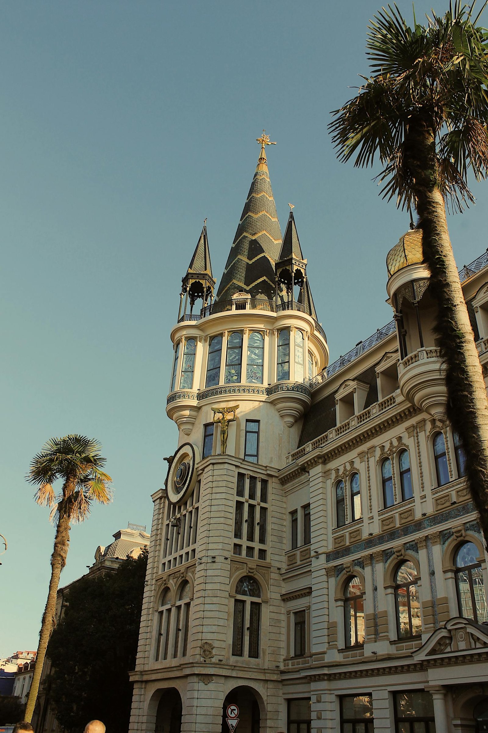 Vintage-style shot of a landmark tower with clock and palm trees under clear sky.